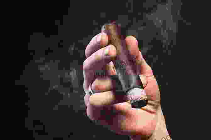 Close Up Of A Hand Holding A Lit Cigar, Smoke Billowing Gently Into The Air Cigars: A Short Guide For Getting Started In The World Of Cigars
